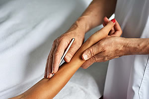 Achtsame Behandlung in der Therapie der Mitte – Balance und Energie im Gleichgewicht Therapeut tastet mit den Händen den Unterarm einer Person ab – achtsame energetische Behandlung in der Therapie der Mitte nach Wolfgang Geiger